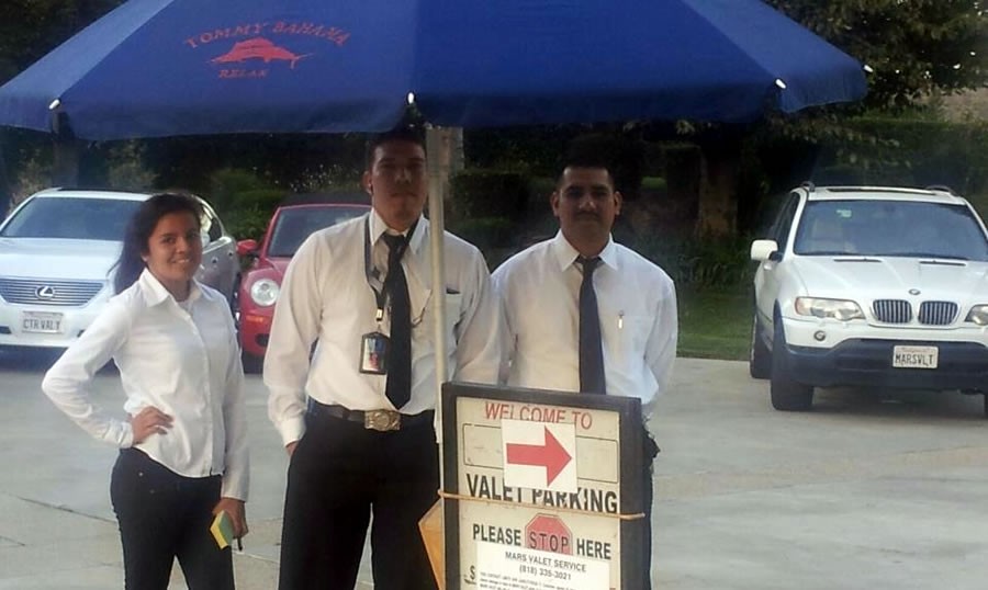 Two men standing next to a sign that says " welcome to valet parking ".
