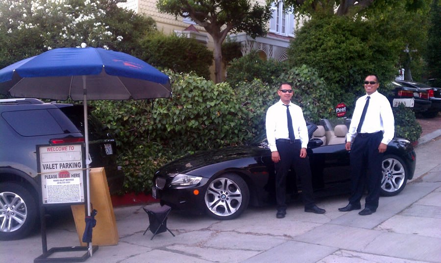A man standing next to a black car.