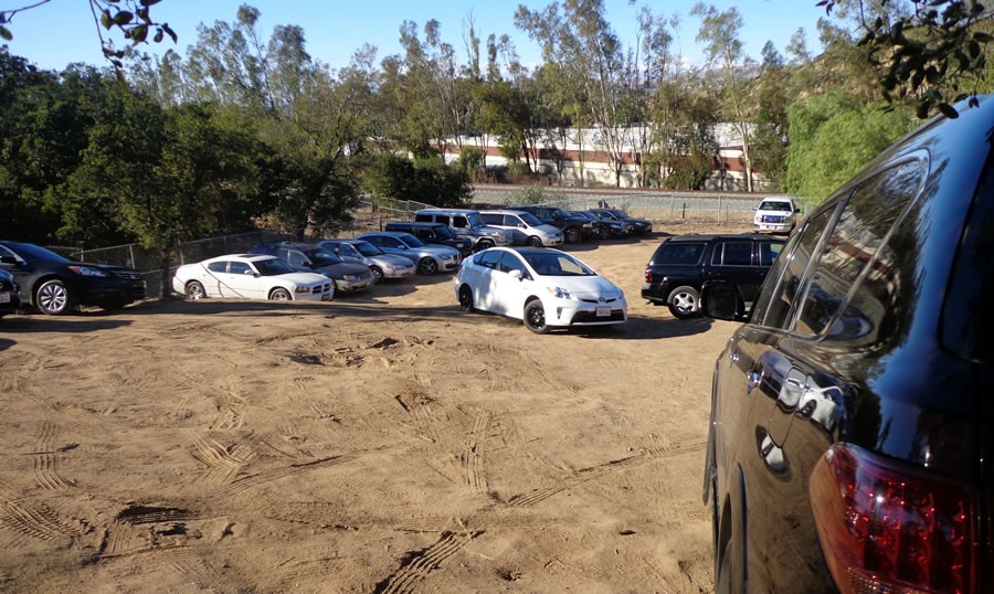 A group of cars parked in the dirt.