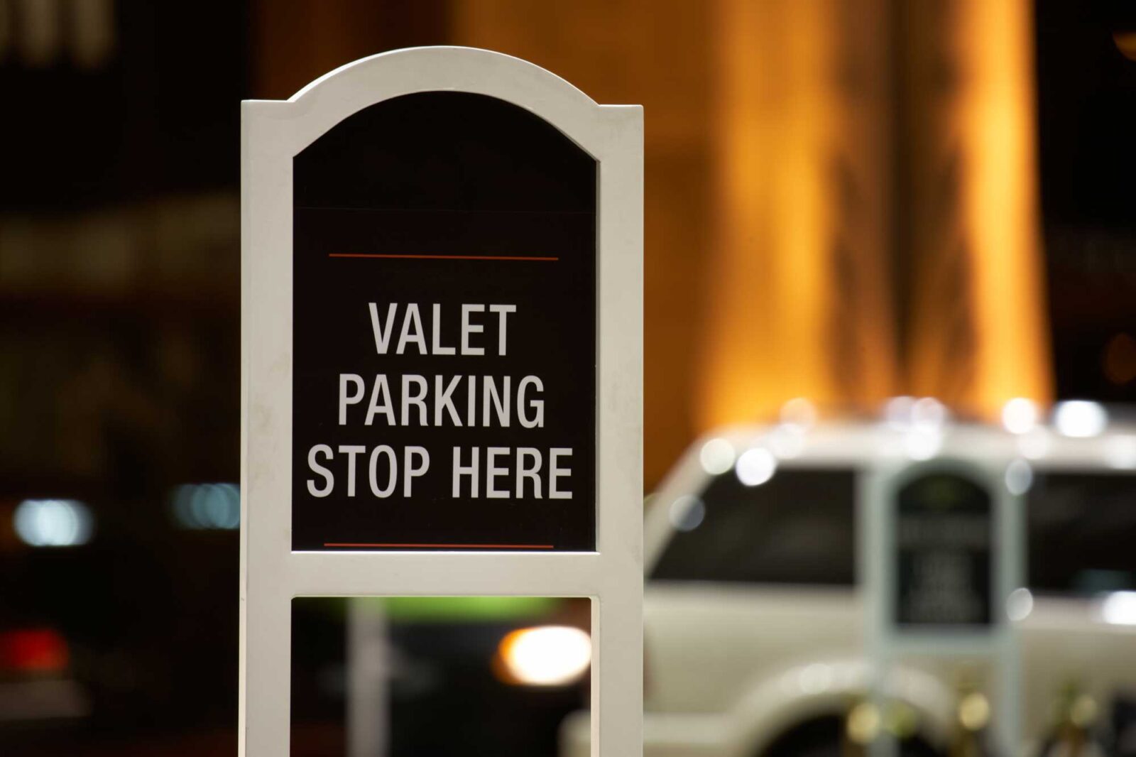 A sign that says valet parking stop here.