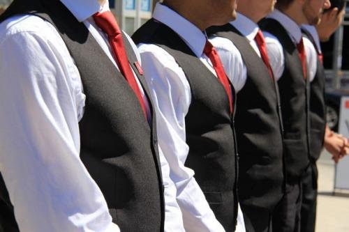 A line of men in vests and ties standing together.