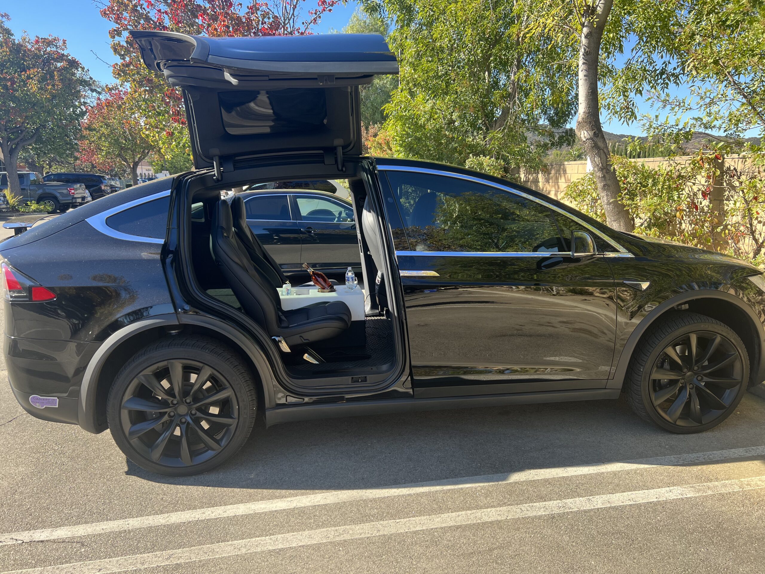 A black car with its doors open on the street.