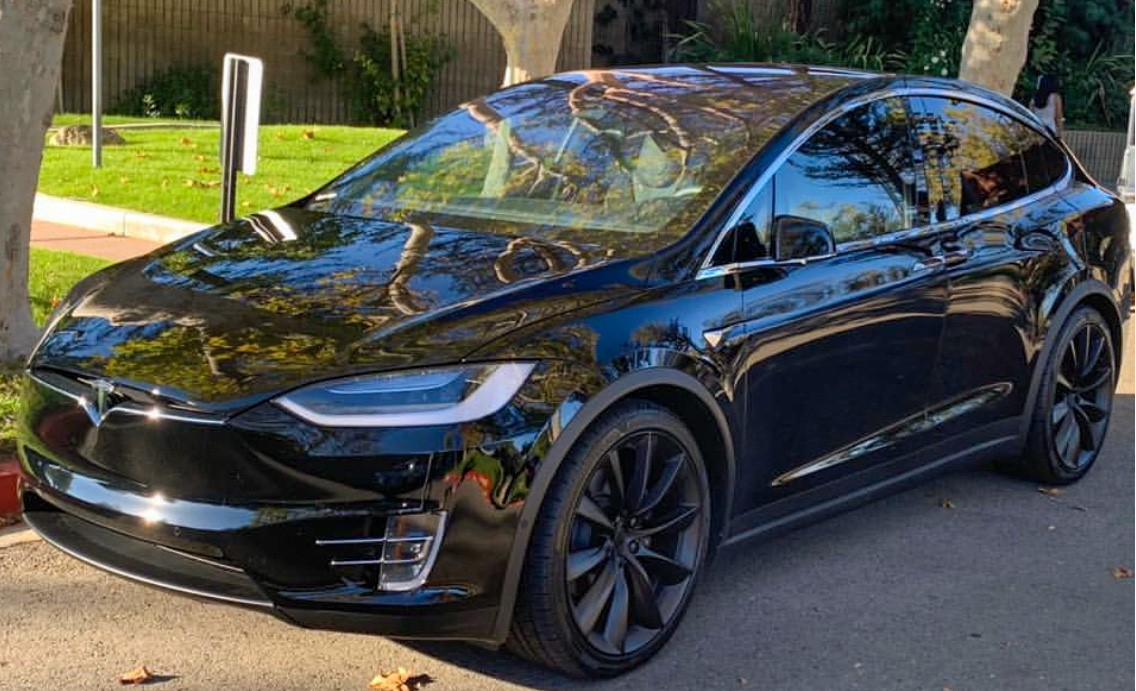 A black tesla parked on the side of a road.